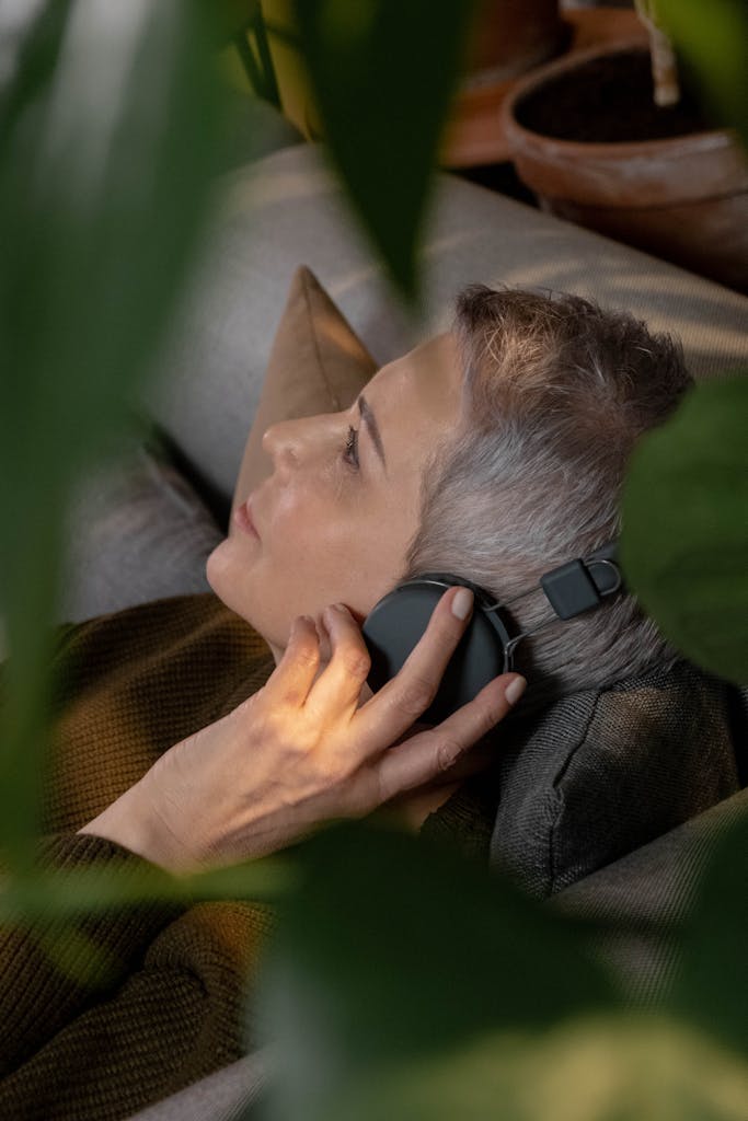 Breathwork Peaceful senior woman with wireless headphones lying on a sofa.
